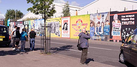 Nordirland - Touristen bestaunen die Wandbilder an der Falls Road in Belfast