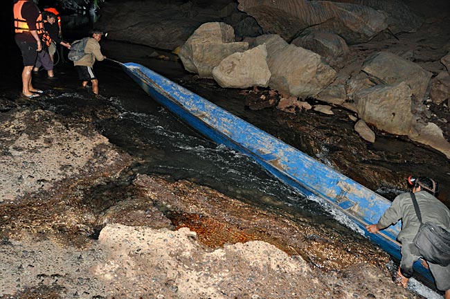 Laos - Karsthöhle bei Konglor - Alle packen an, um das Boot wieder ins Fahrwasser zu bringen